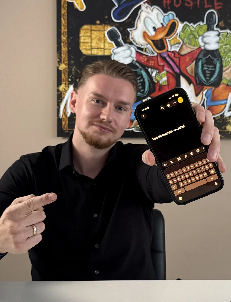 Lothar Niederstein zeigt auf sein Handy mit dem Text Termin buchen