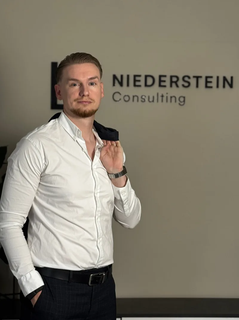 Lothar Niederstein vor dem Logo von Niederstein Consulting